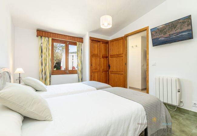 Dormitorio doble de La Sort Llarga – Dos camas y ventana Pollença Dormitorio con dos camas individuales, ventana y armario de madera en La Sort Llarga, Pollença