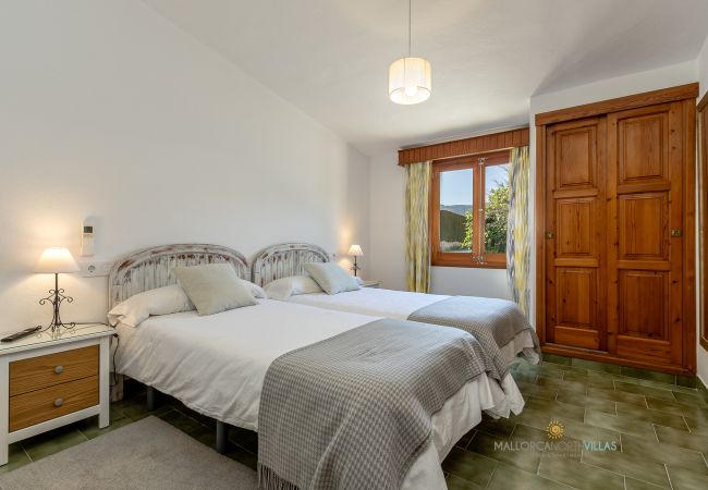 Dormitorio doble La Sort Llarga – Dos camas y armario Pollença Dormitorio con dos camas individuales, armario de madera y ventana al exterior en La Sort Llarga, Pollença