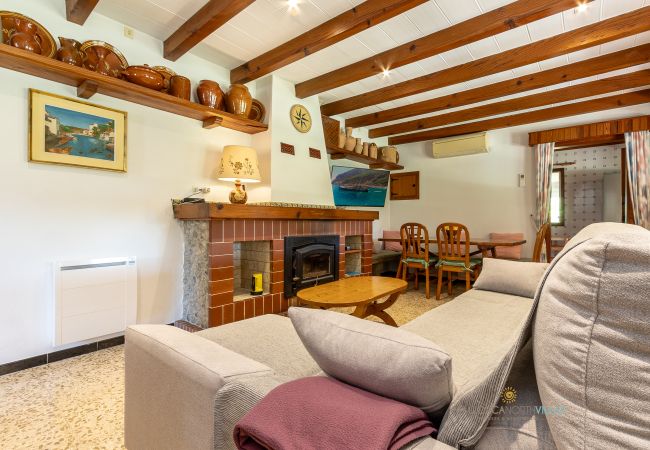 Salón comedor de La Sort Llarga – Interior en Pollença Sofás, chimenea y mesa de comedor en el salón de La Sort Llarga, Pollença