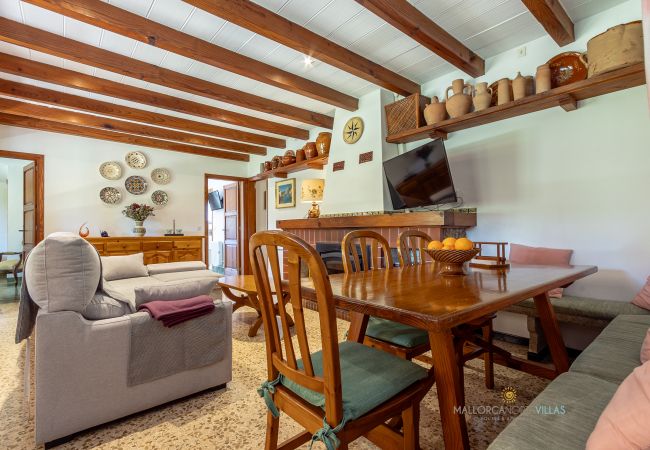 Salón comedor de La Sort Llarga – Mesa y sofás en Pollença Mesa de comedor y sofás en el salón con chimenea de La Sort Llarga, Pollença