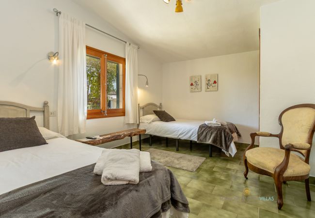 Dormitorio doble con luz natural en La Sort Llarga Habitación con dos camas individuales, ventana y sillón en Pollença