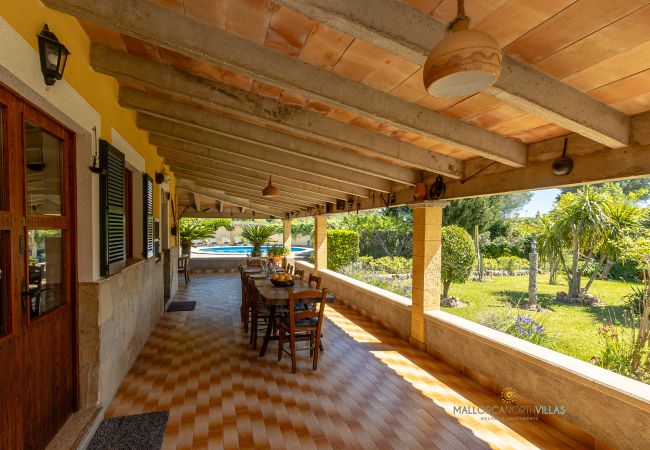 Exterior de La Sort Llarga – Porche con comedor en Pollença Porche con mesa de comedor y vistas al jardín en La Sort Llarga, Pollença