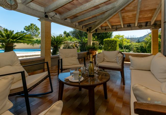 Terraza de La Sort Llarga – Vistas a la piscina en Pollença Sofás y mesa en la terraza cubierta con vistas a la piscina en La Sort Llarga, Pollença