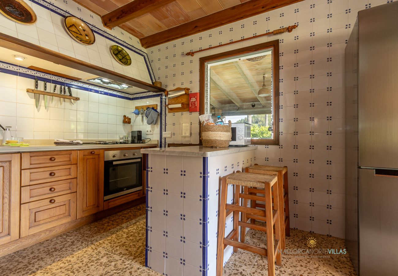 Cocina de La Sort Llarga – Barra y muebles de madera Pollença Cocina con barra, taburetes, horno y muebles de madera en La Sort Llarga, Pollença