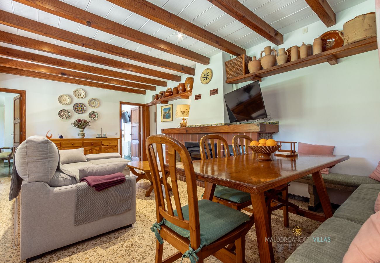 Salón comedor de La Sort Llarga – Mesa y sofás en Pollença Mesa de comedor y sofás en el salón con chimenea de La Sort Llarga, Pollença
