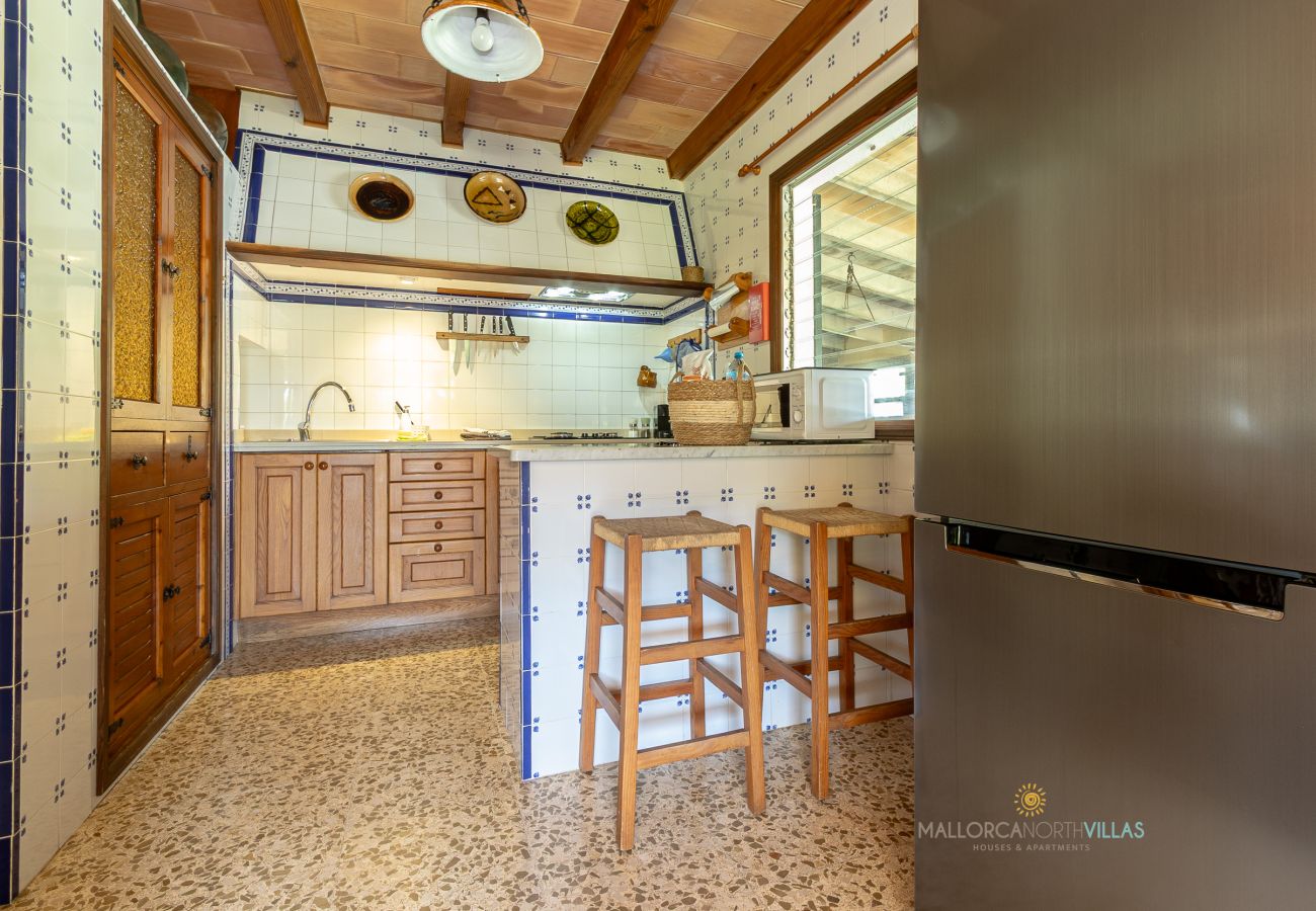 Cocina de La Sort Llarga – Barra y electrodomésticos Pollença Cocina con barra, taburetes, nevera y muebles de madera en La Sort Llarga, Pollença