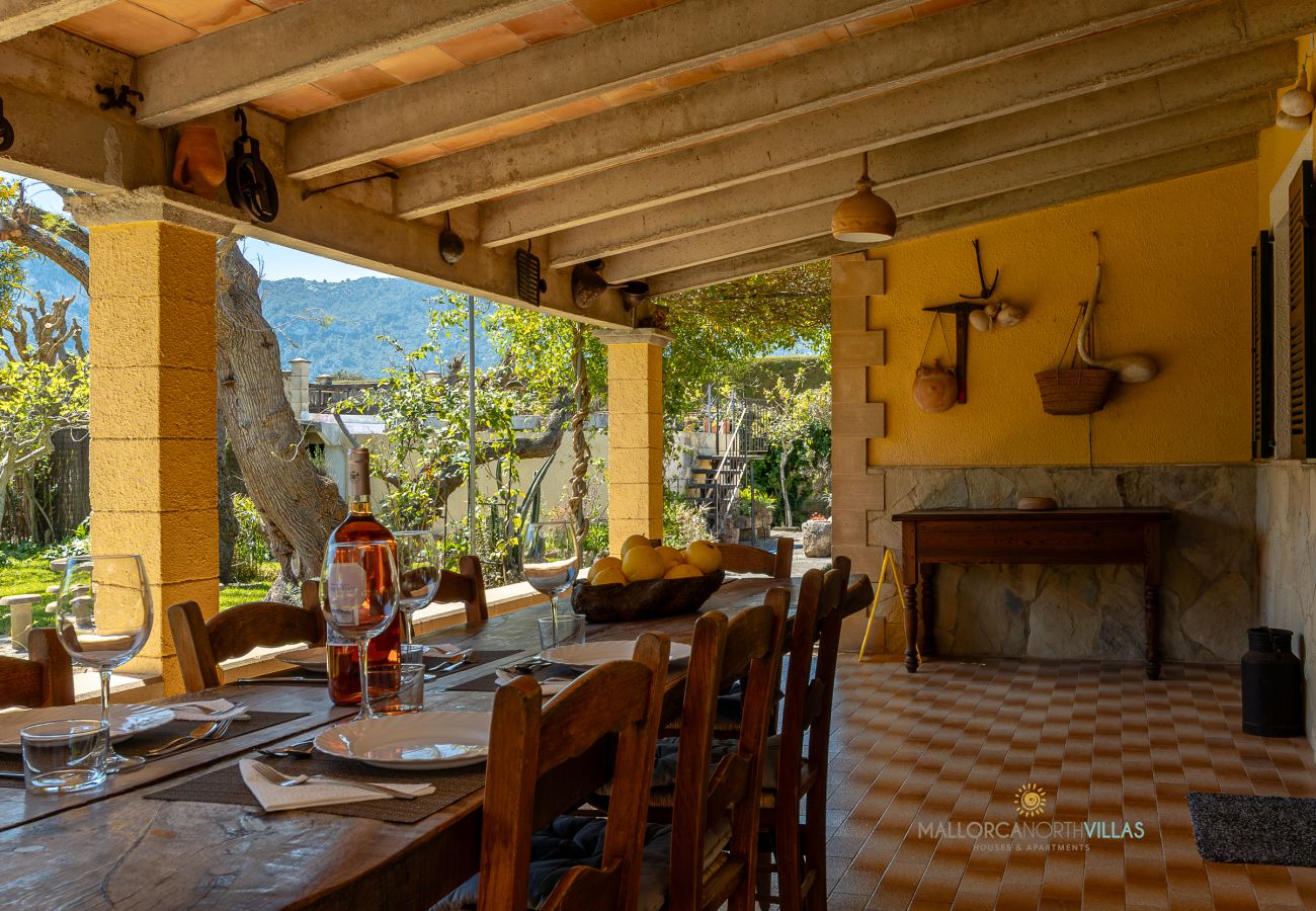 Terraza de La Sort Llarga – Comedor exterior en Pollença Mesa de comedor en terraza exterior con vistas al jardín en La Sort Llarga, Pollença