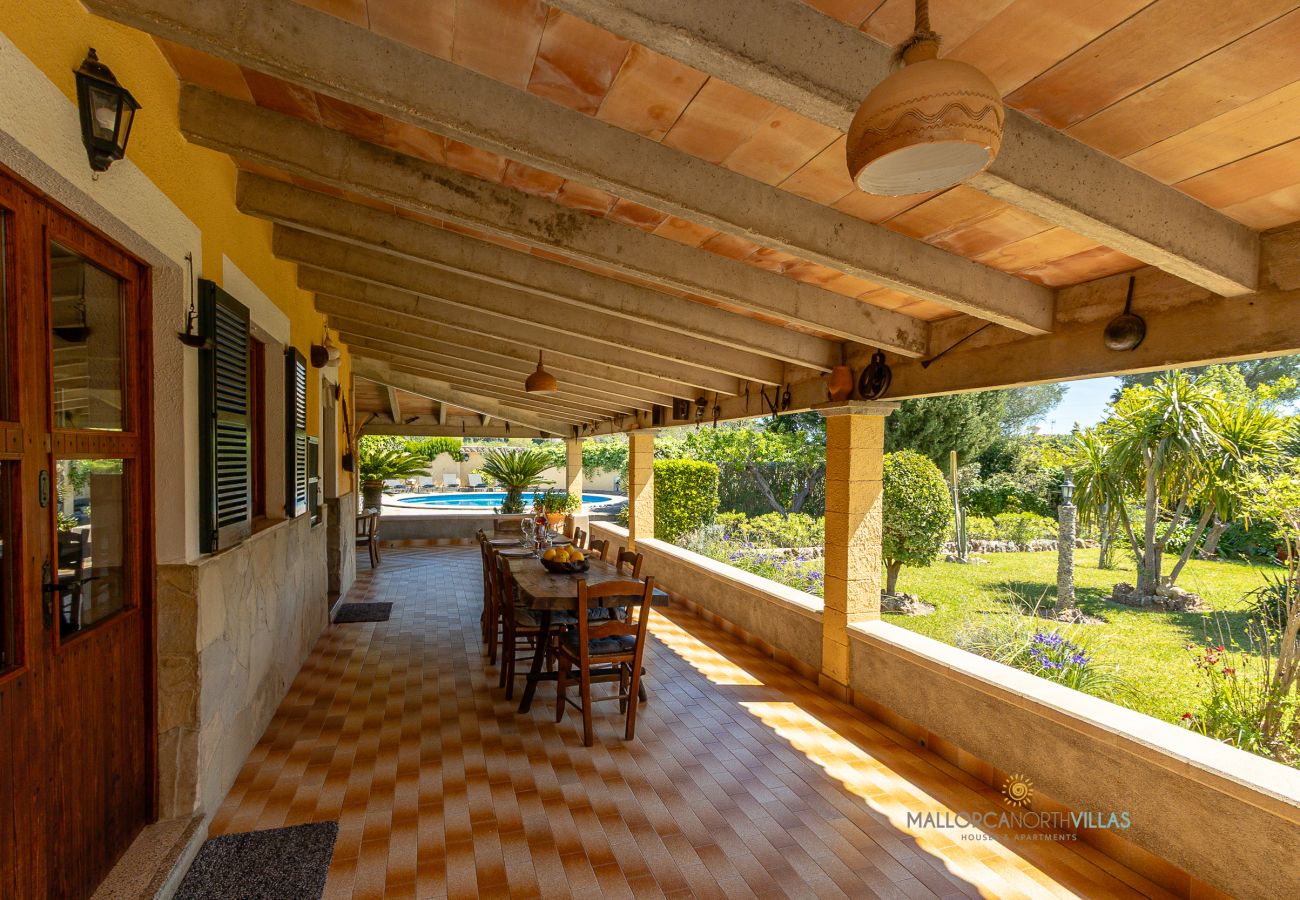 Exterior de La Sort Llarga – Porche con comedor en Pollença Porche con mesa de comedor y vistas al jardín en La Sort Llarga, Pollença