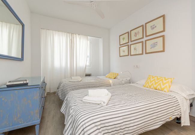 Dormitorio con dos camas y decoración mural Habitación con dos camas individuales, cómoda azul y cuadros en la pared.