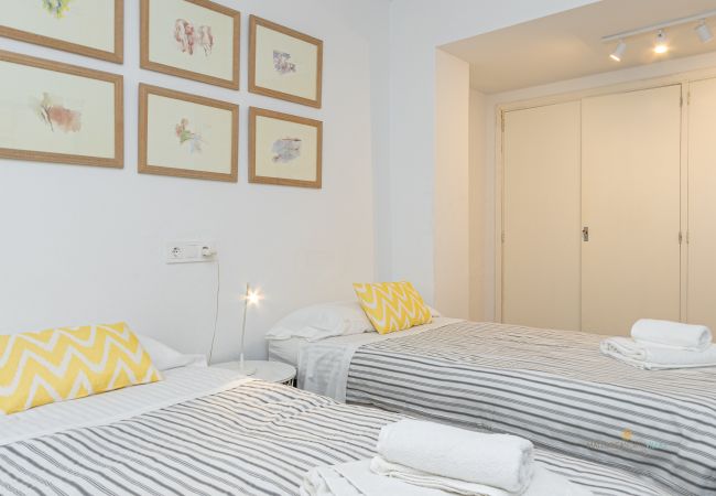 Dormitorio con dos camas y armario empotrado Habitación con dos camas individuales, cómoda azul y cuadros en la pared.