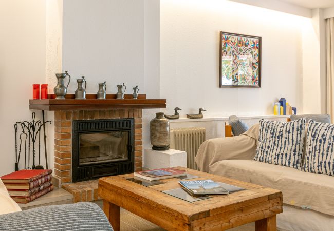 Detalle del salón con chimenea Chimenea de ladrillo con decoración, sofá y mesa de centro con revistas.