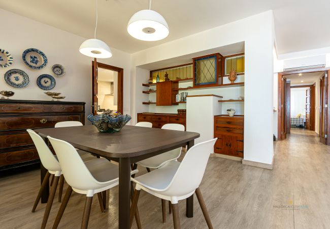 Comedor elegante con aparador y estanterías Mesa de comedor con seis sillas blancas, aparador antiguo y estanterías de madera.