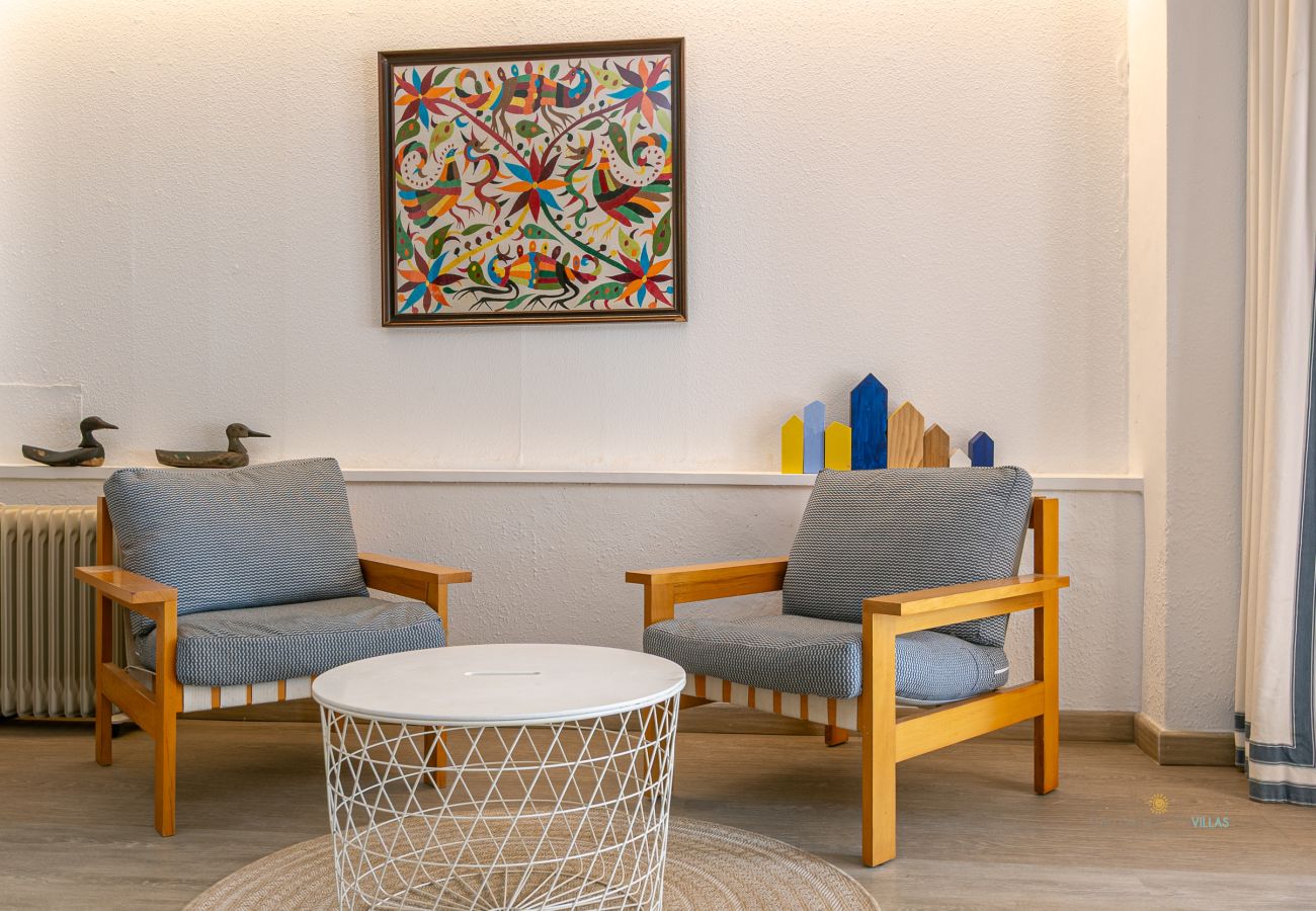 Rincón acogedor con sillones y mesa auxiliar Dos sillones azules con mesa auxiliar blanca y cuadro colorido en la pared.