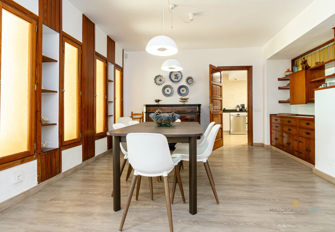 Amplio comedor con muebles de estilo clásico Comedor con mesa rectangular, seis sillas blancas y muebles de madera auxiliares.
