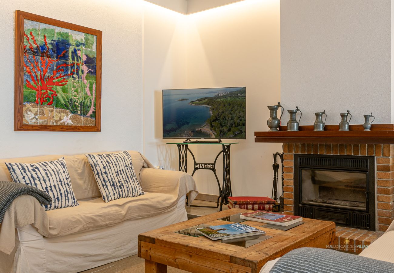 Salón con chimenea y televisión de pantalla plana Sofá con cojines frente a chimenea de ladrillo, mesa de centro y televisor.