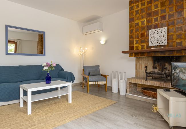 Salón con chimenea y A/A Sofá azul, mesa blanca con flores y chimenea