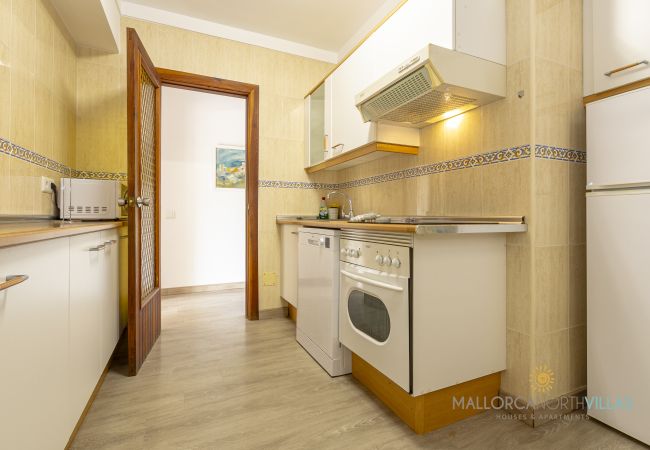 Cocina equipada con electrodomésticos Cocina con muebles blancos, horno, lavavajillas y campana