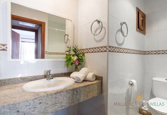 Baño con encimera de granito Lavabo con encimera de granito, espejo y azulejos blancos con cenefa