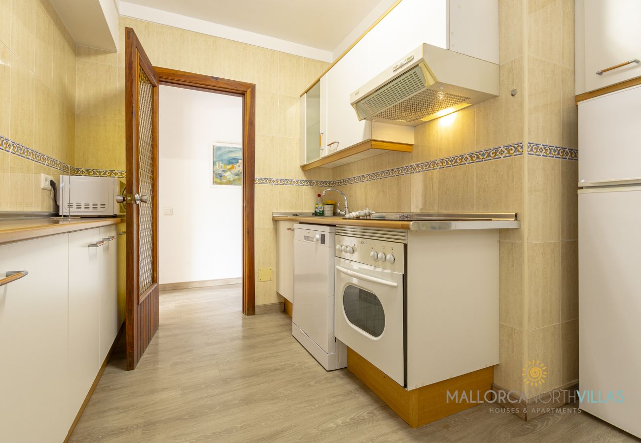 Cocina equipada con electrodomésticos Cocina con muebles blancos, horno, lavavajillas y campana