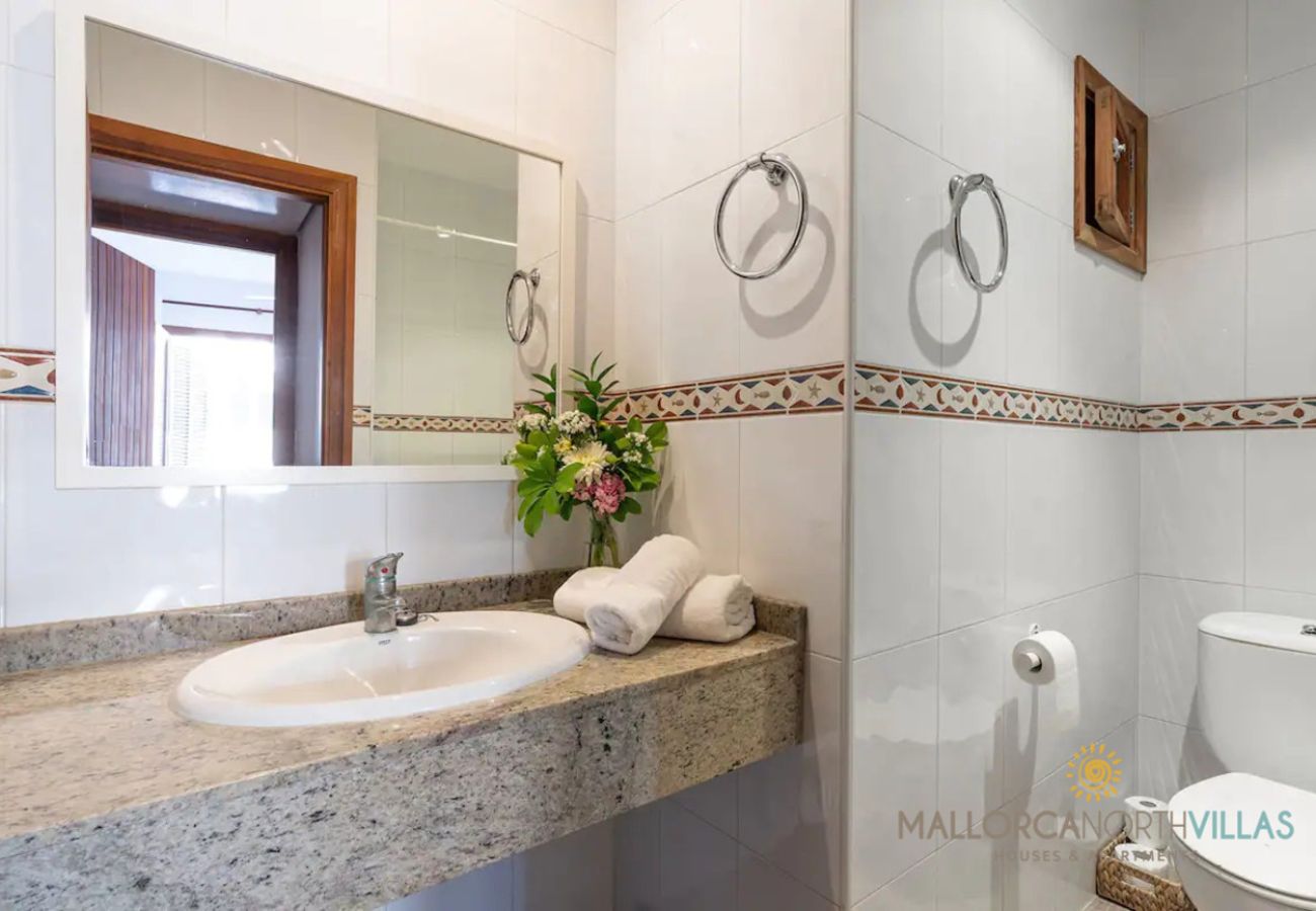 Baño con encimera de granito Lavabo con encimera de granito, espejo y azulejos blancos con cenefa