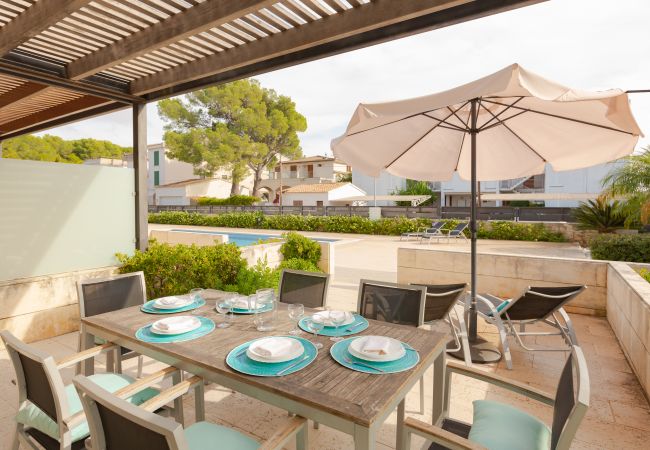Terrasse mit Tisch, Sonnenliegen und Sonnenschirm in Wohnung B Überdachte Terrasse mit Zugang zum Pool