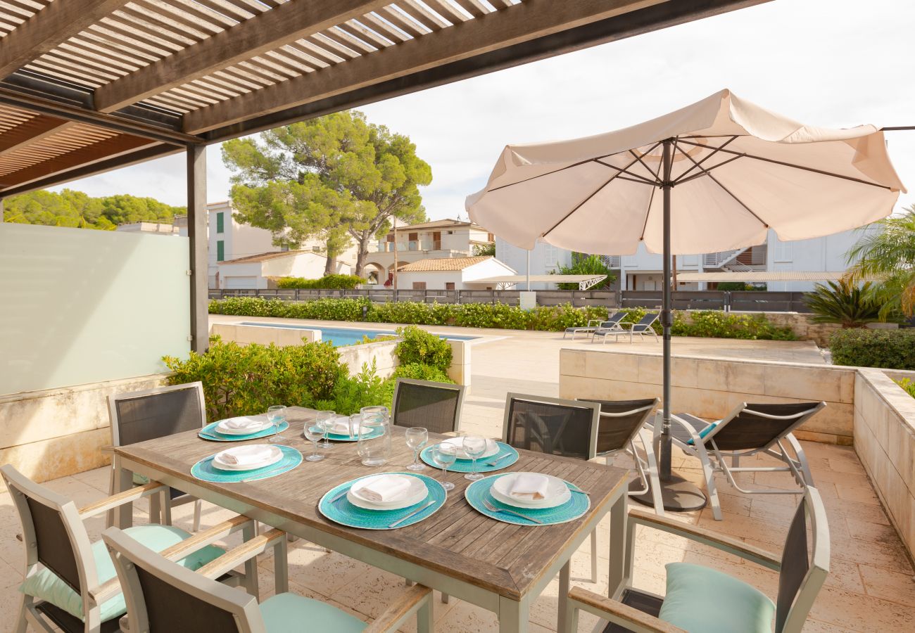 Terrasse mit Tisch, Sonnenliegen und Sonnenschirm in Wohnung B Überdachte Terrasse mit Zugang zum Pool