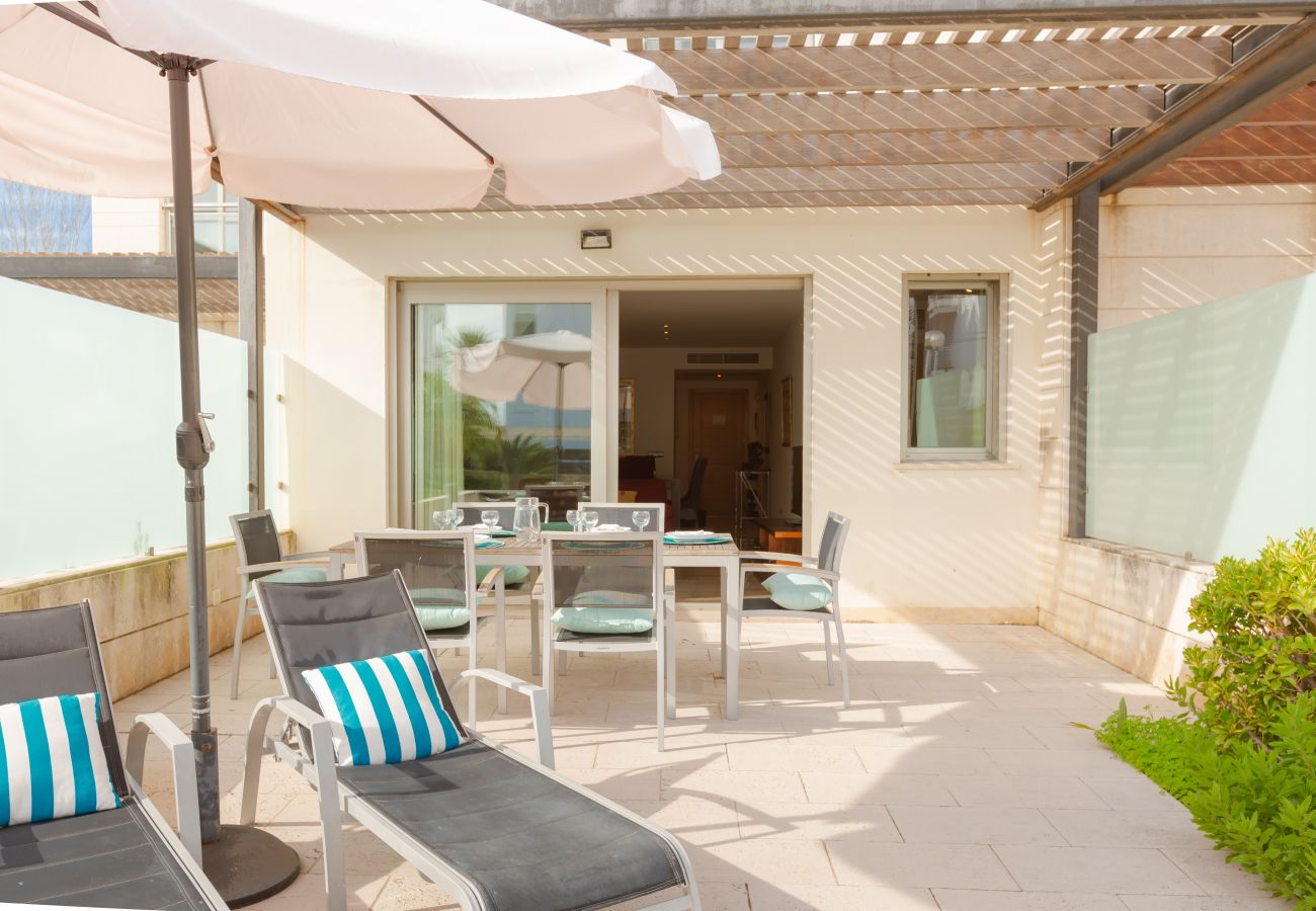 Terrasse mit Sonnenliegen und Sonnenschirmen in La Nau B Terrasse der Wohnung mit Sonnenschirm und Zugang zum Pool