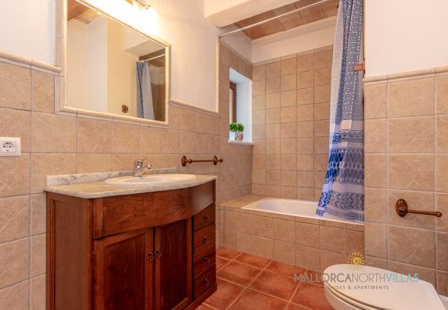 Badezimmer mit Badewanne und Holzwaschtisch Bad mit Badewanne, Holzwaschtisch, großem Spiegel und Fenster nach außen.