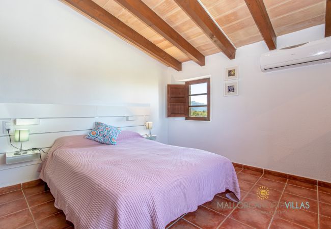 Schlafzimmer mit Doppelbett und Holzbalken sichtbar Schlafzimmer mit Doppelbett, Klimaanlage und sichtbaren Holzbalken in hellem Raum.