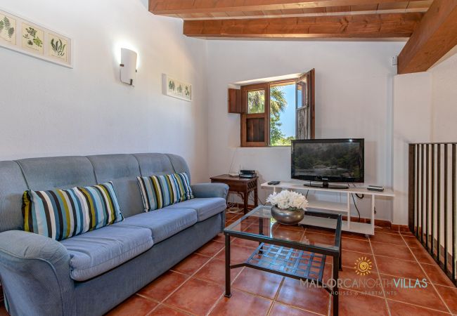 Wohnbereich mit Sofa und mallorquinischem Fenster Wohnbereich mit Sofa, Fernseher und mallorquinischem Holzfenster in traditioneller Finca