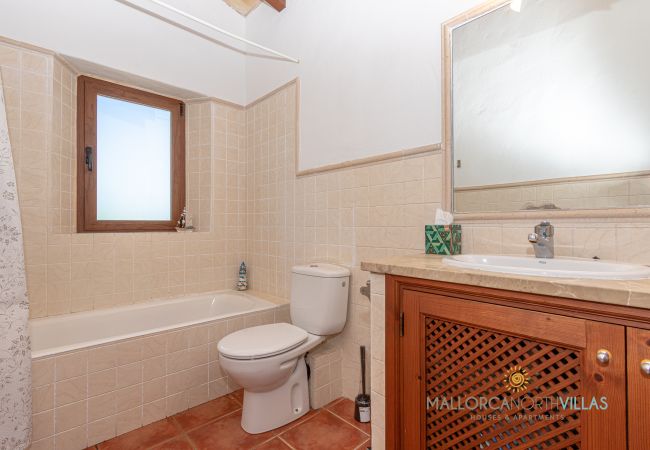 Badezimmer mit Badewanne und Holzwaschtisch Bad mit Badewanne, Holzwaschtisch, Spiegel und Fenster mit Tageslicht.