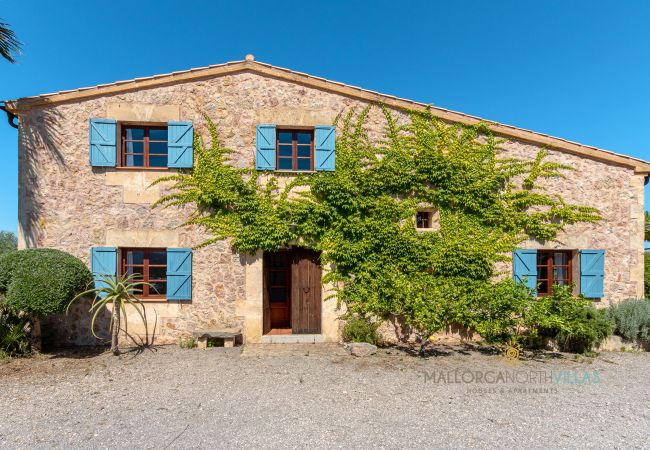 Rustikale Steinfaçade mit Charme in Finca auf Mallorca Steinfaçade mit blauen Fensterläden und Begrünung in mallorquinischer Finca