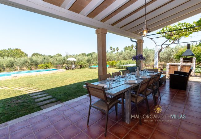 Überdachte Terrasse mit Essbereich in Mallorca Finca Überdachte Terrasse mit Esstisch und Blick auf Garten und Pool in mallorquinischer Finca