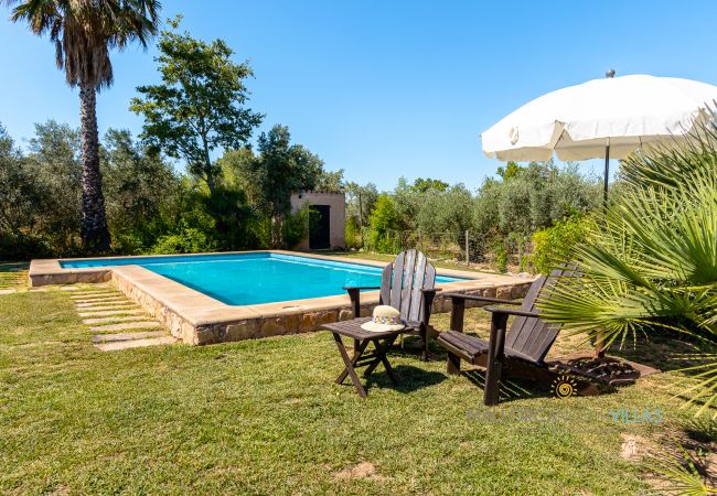 Pool mit Liegen und Sonnenschirm im Garten Privater Pool mit Holzliegen und weißem Sonnenschirm in großem mediterranem Garten.
