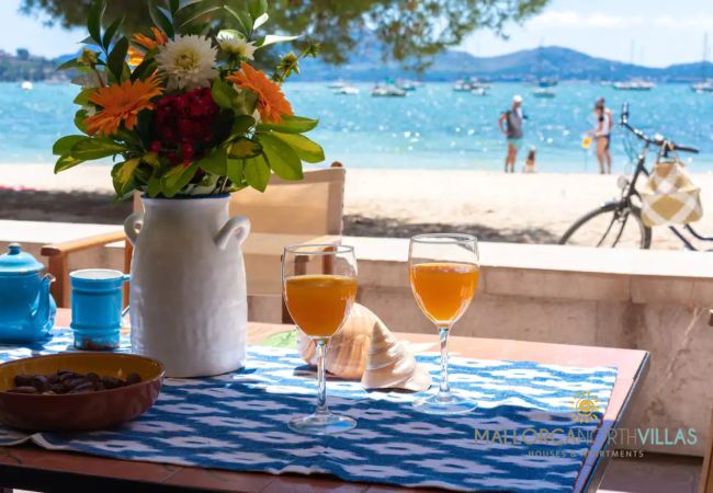 Terrasse am Meer – Puerto de Pollensa Mallorca Terrasse mit Tisch, Getränken und Meerblick in Puerto de Pollensa, nahe der Ferienwohnung Bel by Mallorca North Villas