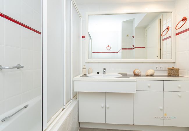 Komplettes Badezimmer mit Badewanne und großem Spiegel Badezimmer mit Badewanne, Waschbecken mit weißem Schrank, großem Spiegel und Deko.
