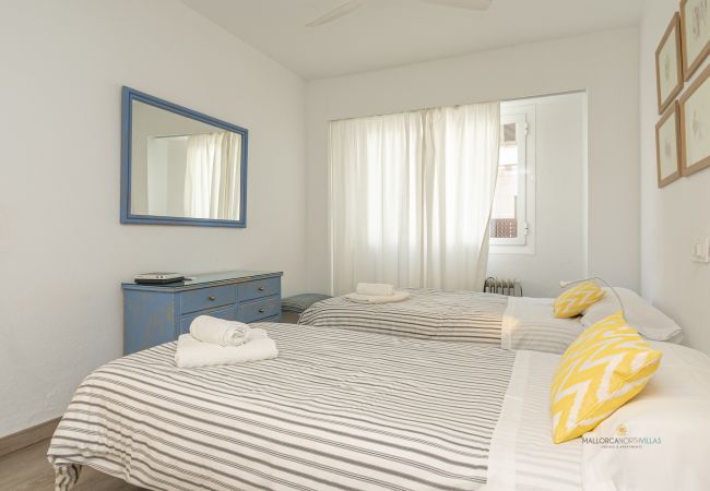 Schlafzimmer mit zwei Einzelbetten Zimmer mit zwei Einzelbetten, gelben Kissen und blauer Kommode mit Spiegel.