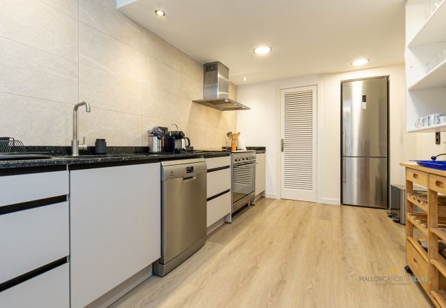 Moderne Küche mit Backofen und großem Kühlschrank Küche mit schwarzer Arbeitsplatte, Geschirrspüler, Backofen, Kühlschrank und Regalen.