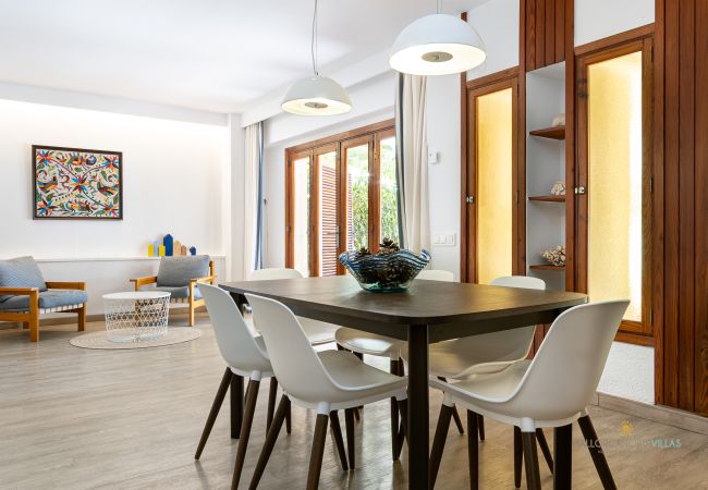 Helles Esszimmer mit Zugang zum Wohnbereich Esstisch mit sechs weißen Stühlen neben einem Wohnbereich mit Sesseln.