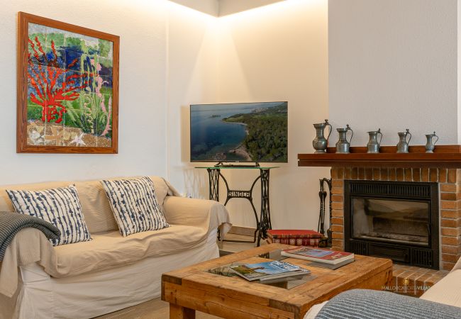 Wohnzimmer mit Kamin und Flachbildfernseher Sofa mit Kissen vor Kamin aus Backstein, Couchtisch und Fernseher.