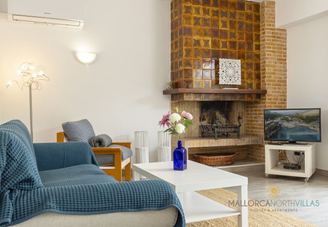 Wohnzimmer mit Kamin und TV Kamin, weißer Tisch mit blauer Flasche und TV