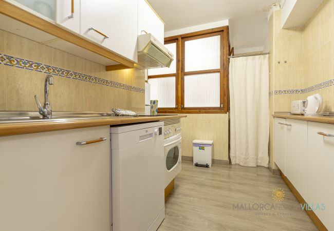 Zeilenküche mit Geschirrspüler Küche mit weißen Schränken, Geschirrspüler, Backofen und Holzfenstern