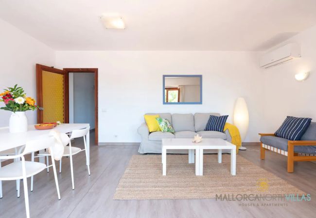 Helles Wohn-Esszimmer mit Klimaanlage Wohnzimmer mit grauem Sofa, Couchtischen und Esstisch mit Blumen