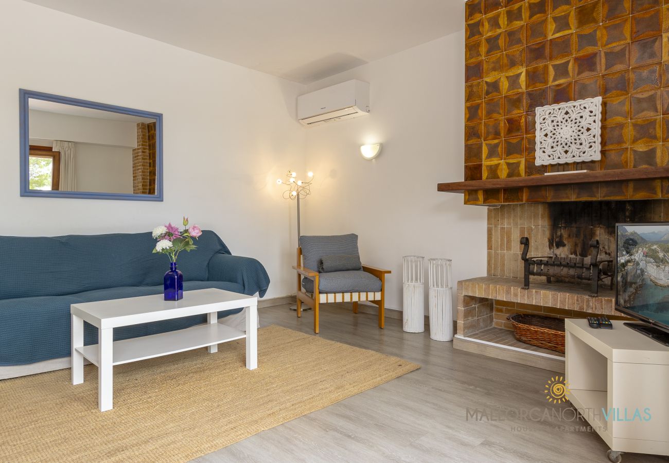 Wohnzimmer mit Kamin und Klimaanlage Blaues Sofa, weißer Tisch mit Blumen und Kamin
