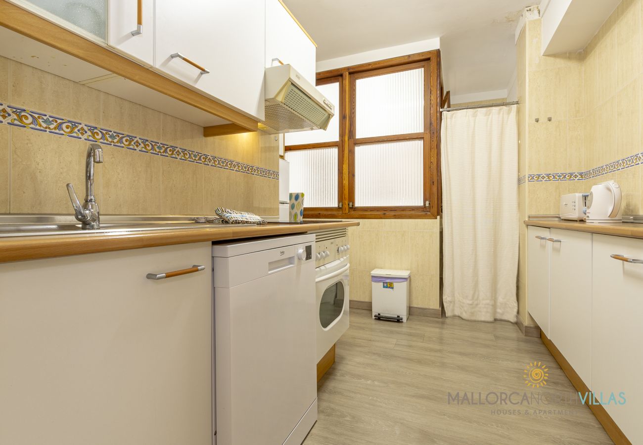 Zeilenküche mit Geschirrspüler Küche mit weißen Schränken, Geschirrspüler, Backofen und Holzfenstern