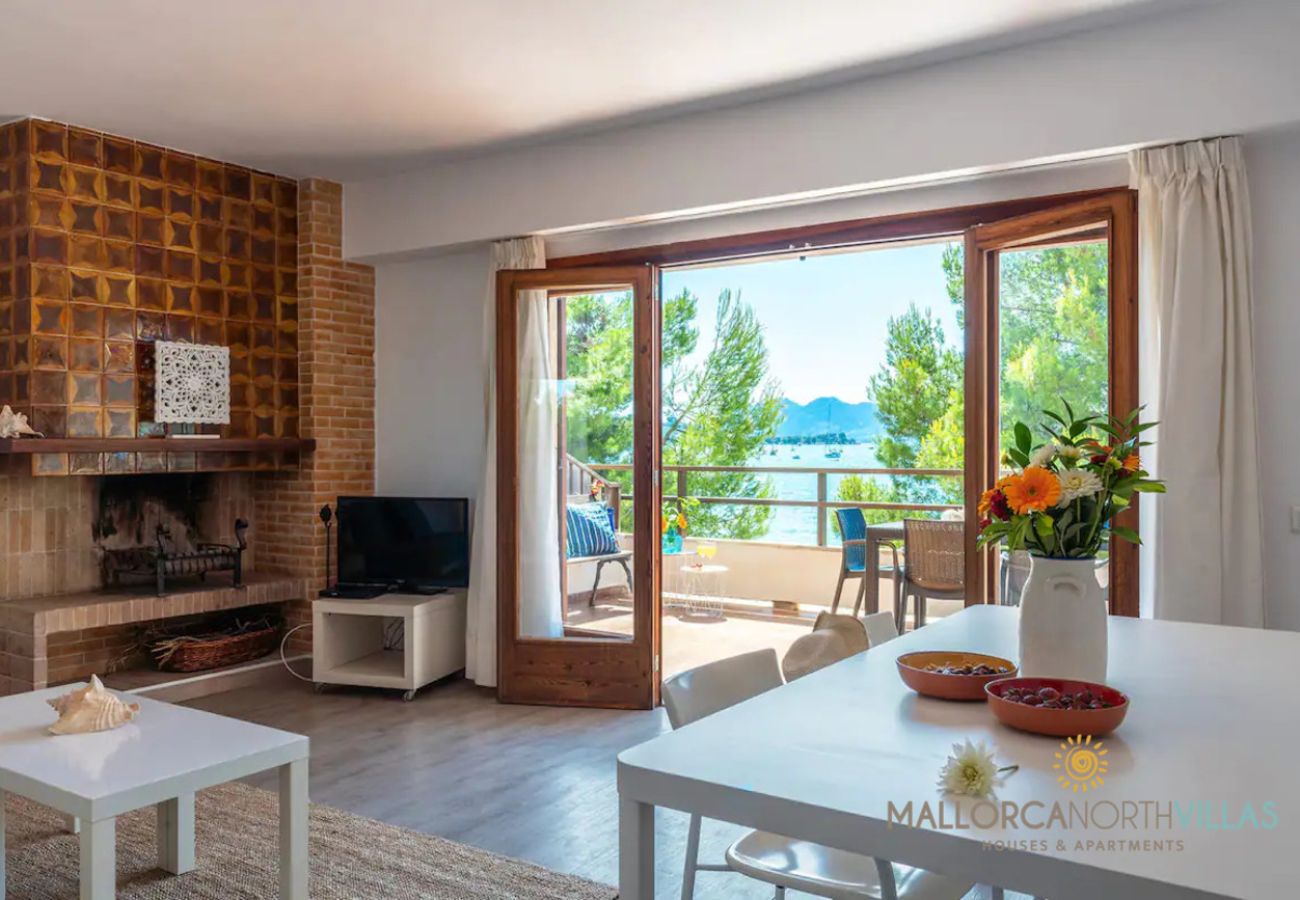Wohnzimmer mit Kamin und Meerblick – Puerto Pollensa Wohnzimmer mit Kamin und Essbereich mit Zugang zur Terrasse und Meerblick in der Ferienwohnung Bel, Pollensa, Mallorca