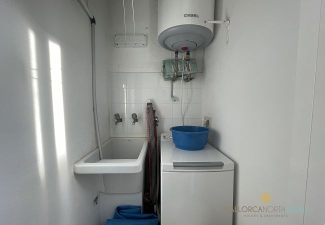 Waschraum mit elektrischem Boiler und Waschmaschine Waschraum mit Waschmaschine, elektrischem Boiler und Spülbecken.
