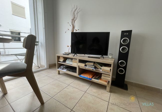 TV-Schrank mit Lautsprecher und Balkon in der Nähe TV-Schrank mit Flachbildschirm, großem Lautsprecher und Büchern, neben einem Balkon mit Tageslicht.