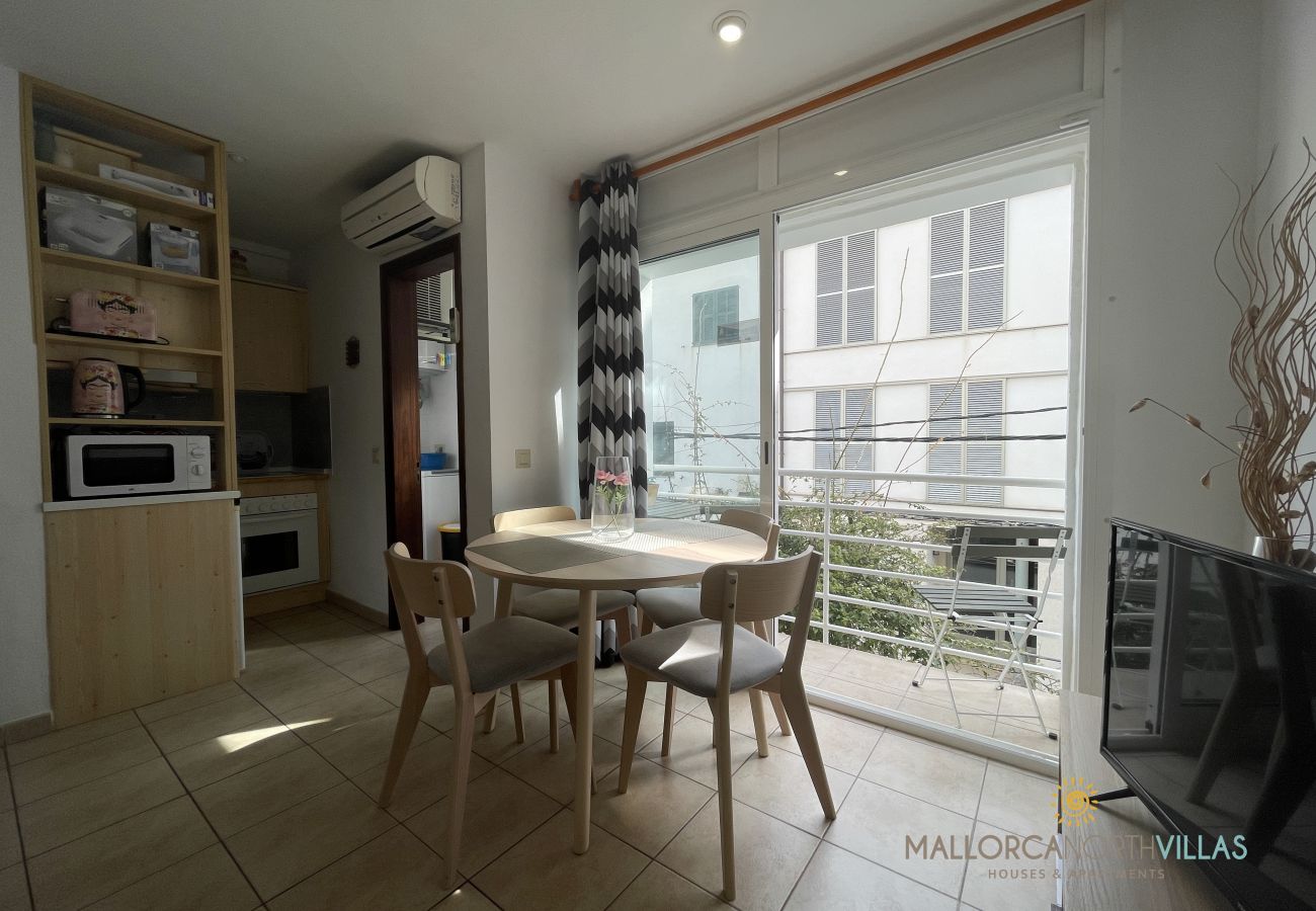 Essbereich mit Balkon und integrierter Küche Essbereich mit Holztisch und Stühlen, Balkonzugang, integrierter Küche und großen Fenstern.