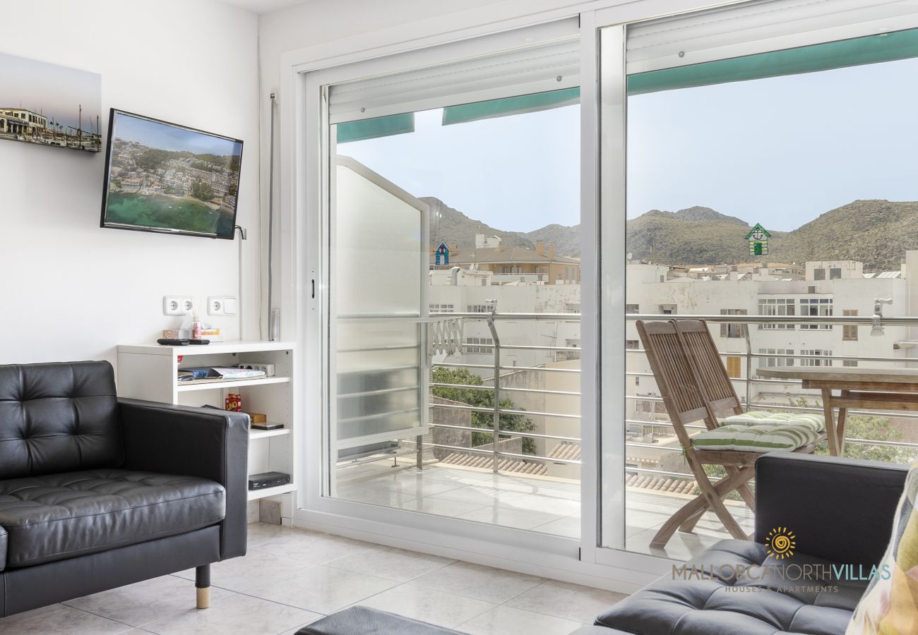 Bright living room with sofa and balcony access overlooking the mountains in Port de Pollença.